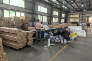 Bedroom furniture packaging preparation area with cartons and workers checking items