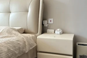 Hotel room bedside cabinet beside an upholstered bed for smart nightstand procurement and project use review