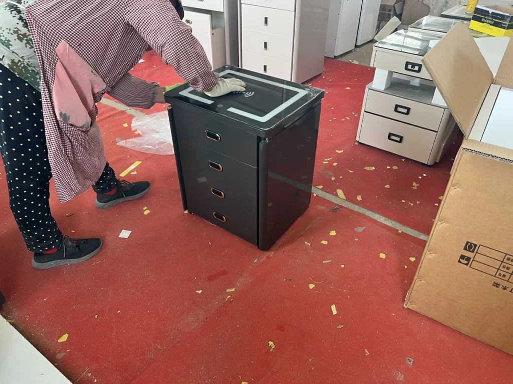 Furniture factory worker checking a bedside cabinet during production with related cabinet components nearby