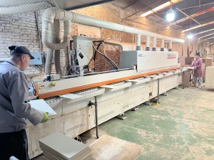 Furniture factory team processing cabinet panels on an edge-banding production line